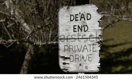 Closeup of weathered wooden sign that says "Dead End | Private Drive"