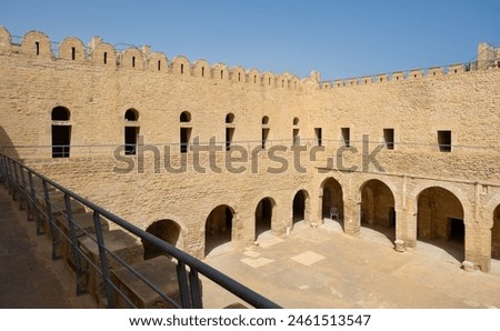 Sunlit inner courtyard of ancient Ribat of Sousse, traditionally flanked by with sturdy stone walls with battlements and shaded arched galleries, Tunisia Royalty-Free Stock Photo #2461513547