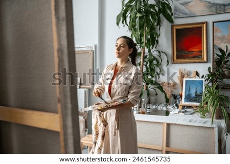Focused artistic female working on painting. Inspired woman painter extremely concentrated on work, make create oil artwork. Girl immersed in creativity process with determination, inner discipline.