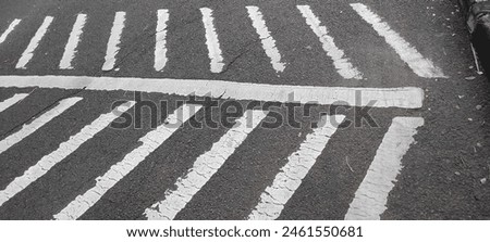 A zebra cross in residential area with white lines on gray asphalt 