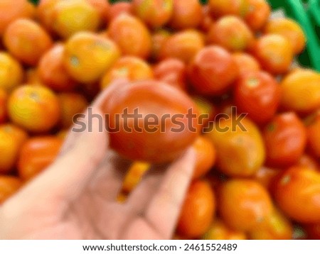 hand holding tomato in blur photo concept