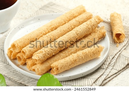 Egg Roll Biscuit or Kue Semprong or sapit, Simping, kue Belanda, or kapit or Love letters in English. It is an Indonesian traditional wafer snack or kuih. Royalty-Free Stock Photo #2461552849