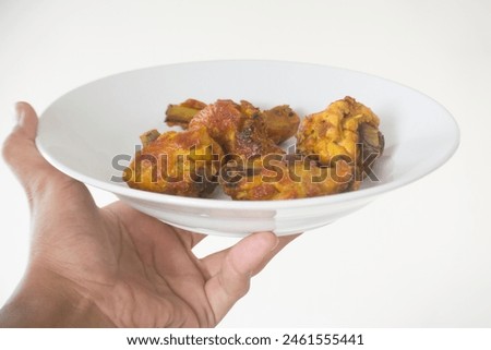 Hand giving pieces of fried chicken on a glass plate