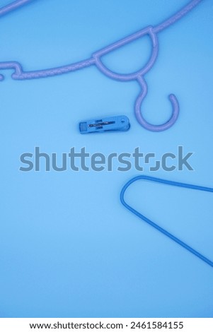 Plastic household items for clothes. Top view clothespins and hangers with blue background. Blue concept of household items for fabric and textiles. Blue clothespins and hangers with copy space. 