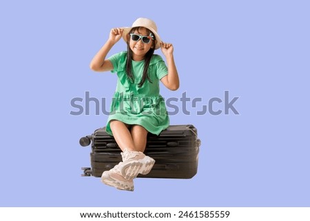 Happy smiling asian little girl were hat and sunglasses posing with sitting on a suitcase, Travel fashion summer holiday concept, Full body isolated on pastel purple color background 
