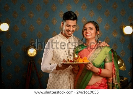Cute Couple Pic celebrating Diwali in traditional Indian attire, grinning, and carrying a puja plate in their hands
