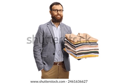 Bearded man holding folded clothes and smiling at camera isolated on a white background