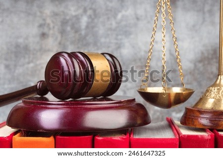 Law concept - Open law book, Judge's gavel, scales, Themis statue on table in a courtroom or law enforcement office. Wooden table, gray concrete background.