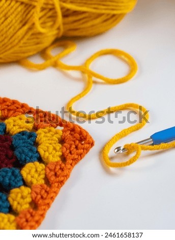 Beautiful pattern of yellow yarn with blue hook on white background. High quality photo