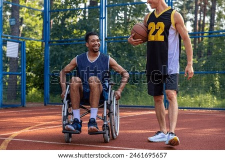 Friends playing basketball on court man in wheelchair having workout