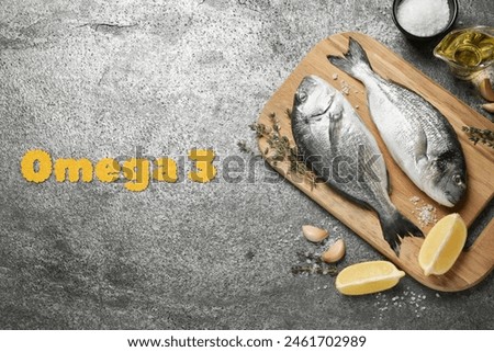 Omega 3. Fresh dorado fish, oil, lemon and spices on grey table, flat lay