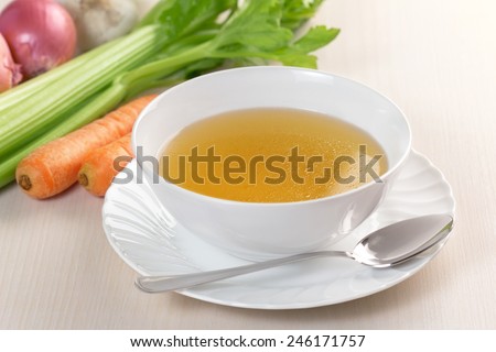 bowl of broth and fresh vegetables on wooden table Royalty-Free Stock Photo #246171757