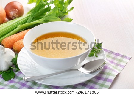bowl of broth and fresh vegetables on wooden table Royalty-Free Stock Photo #246171805