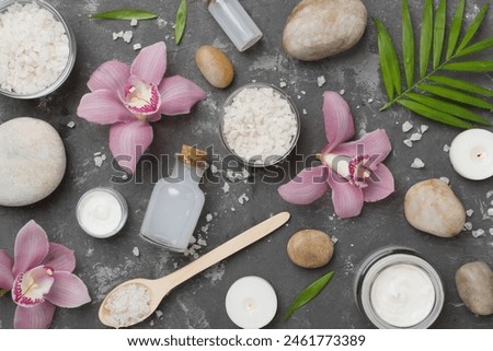 Composition with orchids and massage stones on concrete background, top view