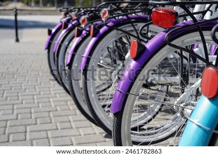 A row of bicycles wheels for rent standing in the street