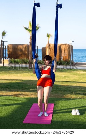 Woman tourist doing aerial gymnastics on fabrics on vacation in a hotel.