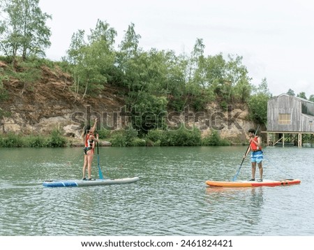 Friends paddleboarding on lake stock photo