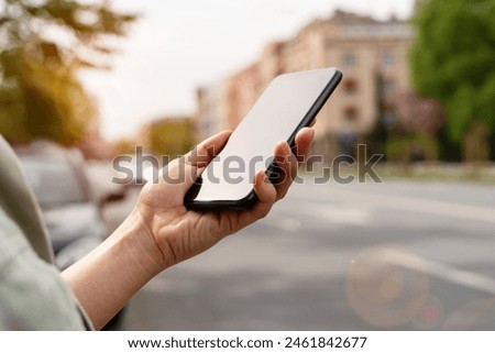 Touchscreen mobile phone in woman's hand closeup against city street.