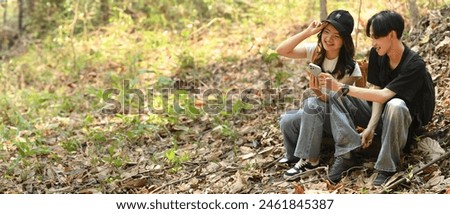 Young friends using a smartphone to explore routes to begin their journey, while hiking in the woods, Banner cover.