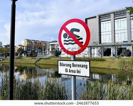 Do not swim sign near a lake in Indonesian language. 