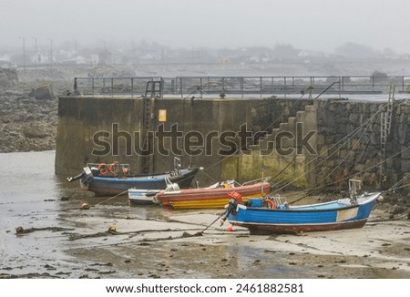Boats moored in a empty harbour after the tide has gone out on a misty Spring afternoon Royalty-Free Stock Photo #2461882581