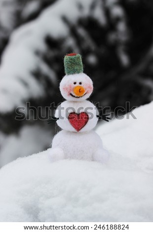 toy snowman on snow cover with pink heart, outdoor. valentines day card.