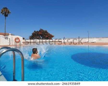 holiday photo, boy splashing in the pool, tropical background with blue sky