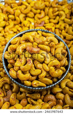 Close-Up of Saffron Cashews in a Decorative Bowl, A high-resolution image showcasing saffron-infused cashews in a decorative blue and white bowl, ideal for culinary use and healthy snacking.