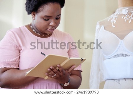 Black woman, fashion design and planning with book in office for project, strategy or brainstorming. Creative, industry and designer with writing at work for boutique, schedule or journal of progress