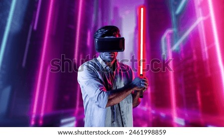 Gamer holding laser sword and playing action game while wearing VR glasses. Caucasian man using visual reality headset while standing and surrounding by neon castle. Innovation technology. Deviation.