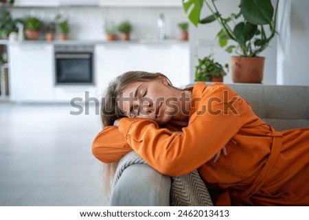 Woman put head on armrest resting on comfy sofa after working day, napping, closed eyes. Portrait relaxed female spending lazy time on couch in living room. Leisure, repose concept Royalty-Free Stock Photo #2462013413