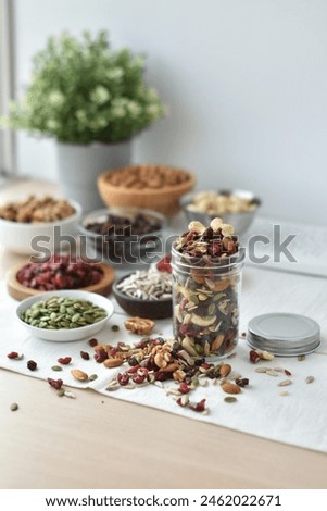 A vibrant and nutritious trail mix featuring goji berries, pumpkin seeds, sunflower seeds, chocolate-covered raisins, almonds, dried cranberries, cashews, and walnuts.