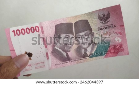 Close up of man's hand holding Indonesian 100000 rupiah banknotes, money financial management concept. Soft focus, Selective focus
