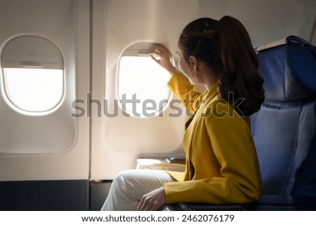 Confident businesswoman in formal clothes looking out of airplane window during flight while working on laptop computer Online internet connection, travel concept, business tourism.