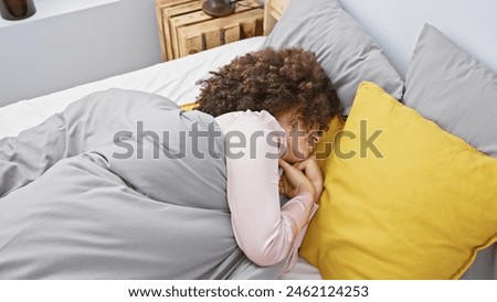 Young hispanic woman with curly hair sleeping in a cozy bedroom, embodying tranquility and comfort at home. Royalty-Free Stock Photo #2462124253