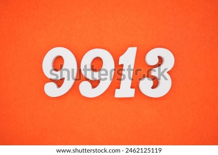 The number 9913 is made from white painted wood placed on a background of orange paper.