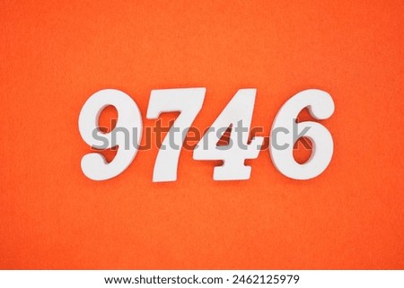 The number 9746 is made from white painted wood placed on a background of orange paper.