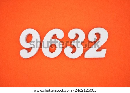The number 9632 is made from white painted wood placed on a background of orange paper.