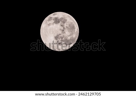 A large, full moon is shining brightly in the night sky. Concept of calm and serenity, as the moon's light illuminates the darkness. The contrast between the bright moon