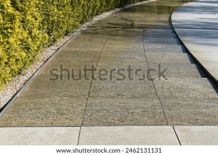City park Krasnodar. Artificial swift river with granite banks runs around evergreen hedge with rest area. Public landscape 'Galitsky park' for relaxation and walking in sunny spring 2024 Royalty-Free Stock Photo #2462131131