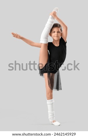 Little girl doing gymnastics on light background