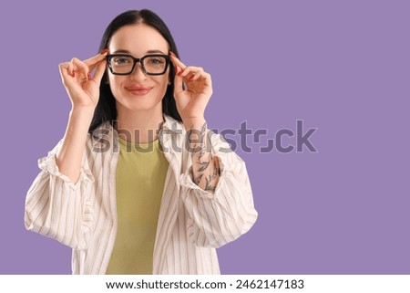 Young woman in eyeglasses on lilac background