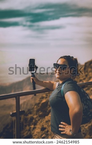 Woman on the mountain films the view of the mountains with her phone camera