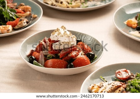 Fresh greek salad in a plate on a table with other dishes. Healthy vegetarian food. Copy space