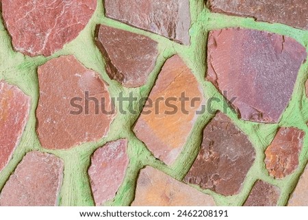 It is a photo of colorful stones on green background. Its close up of multicolored stone wall of building. It is photo of mosaic tile floor. It's view of wall texture.
