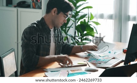 Professional designer looking and designing logo graphic at meeting. Closeup of business man working on colored palettes and writing idea on sticky notes on table with equipment and paper. Symposium.