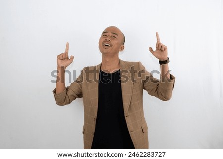 Asian bald businessman stands pointing up, advertising and copy space, isolated against a white background.