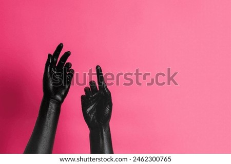 Elegant woman's hands with black paint on her skin on a pink background. High Fashion art concept