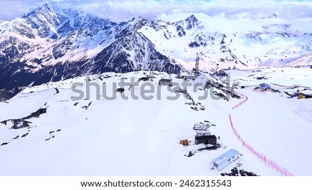 The snow-covered mountain range, with its snow-capped peaks and cozy cabins, creates a serene and picturesque scene. Royalty-Free Stock Photo #2462315543