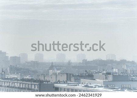 Panoramic view of the city of Warsaw, Poland in Eastern Europe on a cold winter day. There is snow and fog that blurs the four Soviet-era towers in the background